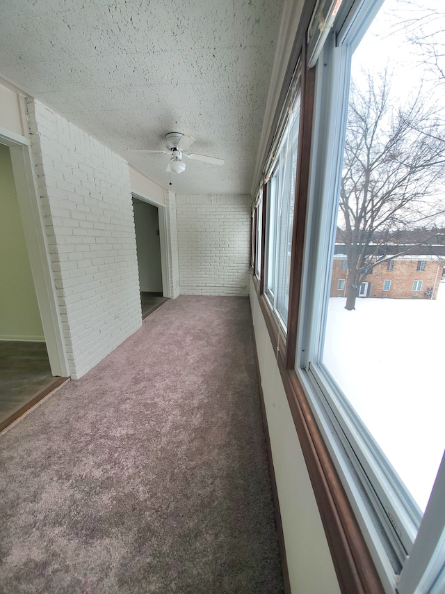 spare room with brick wall, carpet floors, a ceiling fan, and a textured ceiling
