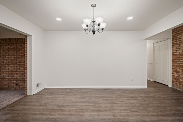 unfurnished dining area featuring dark wood-style floors, a chandelier, brick wall, baseboards, and recessed lighting
