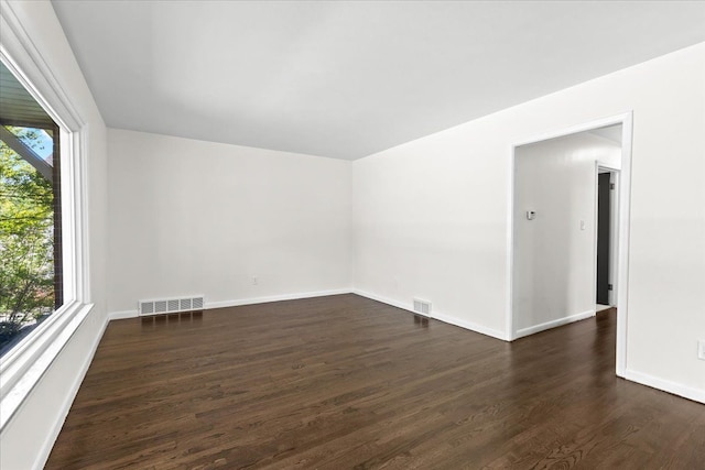 spare room featuring dark wood-style flooring and baseboards