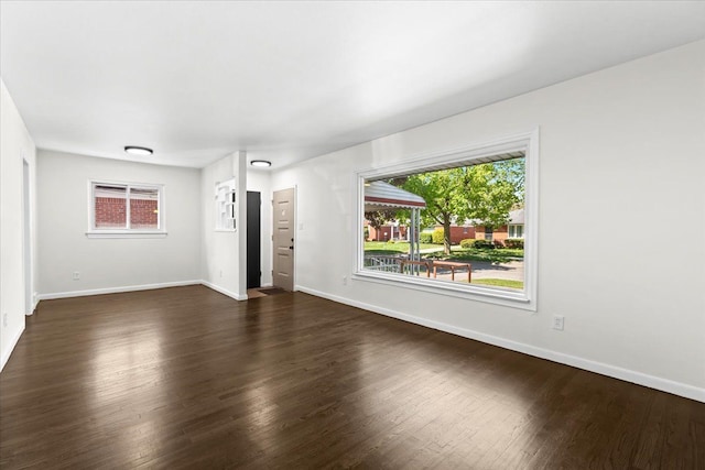 unfurnished living room with dark wood-style floors, baseboards, and plenty of natural light