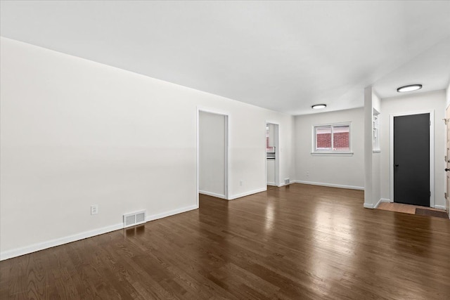 unfurnished living room featuring dark wood-style flooring and baseboards