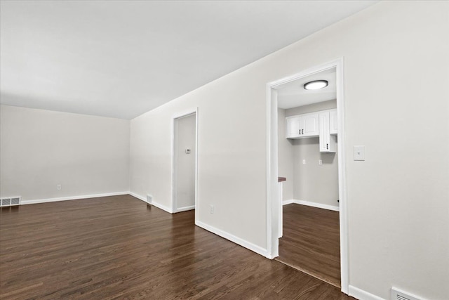 spare room featuring dark wood-style floors and baseboards