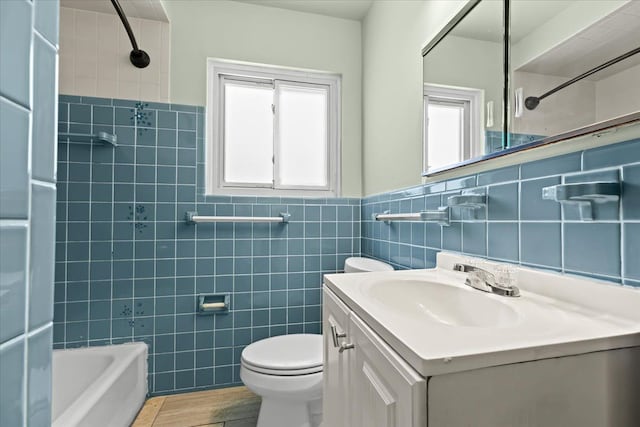 bathroom with toilet, tile walls, vanity, bathing tub / shower combination, and wood finished floors