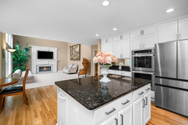 1433 Bicentennial Pkwy, Ann Arbor, MI 48108 - kitchen with appliances with stainless steel finishes, open floor plan, a glass covered fireplace, white cabinets, and recessed lighting