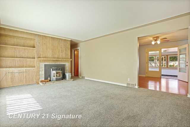 1415 Coolidge Ave, Saginaw, MI 48638 - unfurnished living room with carpet flooring, a wood stove, ceiling fan, and baseboards