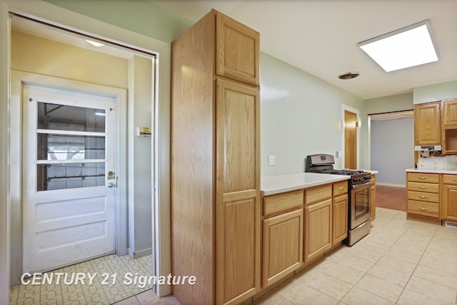 1415 Coolidge Ave, Saginaw, MI 48638 - kitchen featuring gas range, light countertops, light tile patterned floors, and a skylight