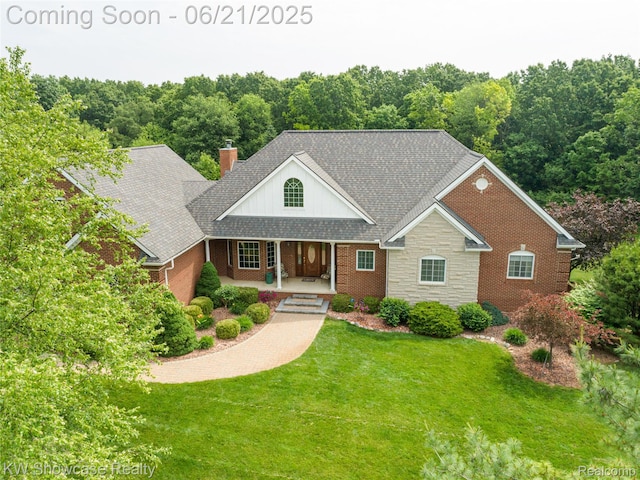 2449 Woodvale Trl, Brighton, MI 48114 - view of front facade featuring covered porch, a front lawn, brick siding, stone siding, and a chimney