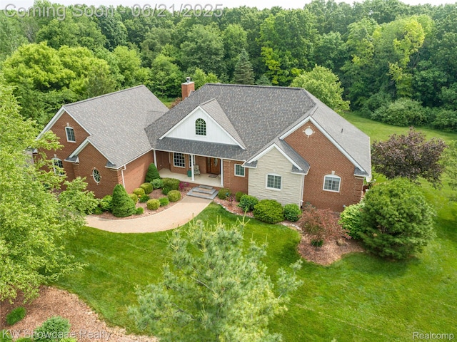 2449 Woodvale Trl, Brighton, MI 48114 - view of front of house featuring a porch, a front lawn, brick siding, a chimney, and roof with shingles