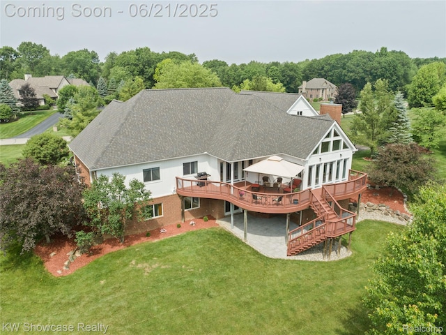 2449 Woodvale Trl, Brighton, MI 48114 - rear view of house featuring a wooden deck, a shingled roof, a lawn, and a chimney