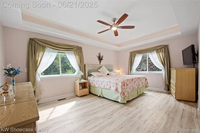 2449 Woodvale Trl, Brighton, MI 48114 - bedroom with a tray ceiling, multiple windows, light wood finished floors, and ceiling fan