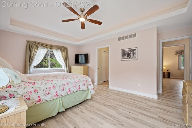 2449 Woodvale Trl, Brighton, MI 48114 - bedroom with a tray ceiling, light wood-style floors, and a ceiling fan