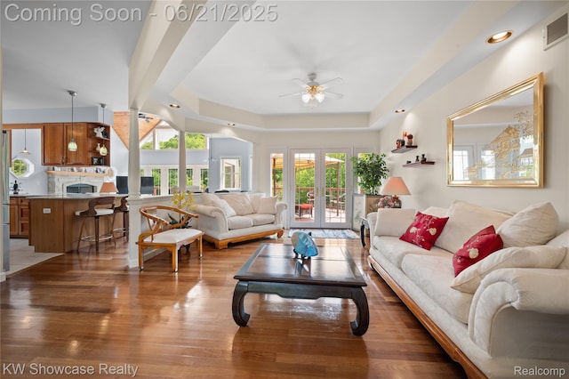 2449 Woodvale Trl, Brighton, MI 48114 - living room with a ceiling fan, wood finished floors, french doors, a tray ceiling, and a fireplace