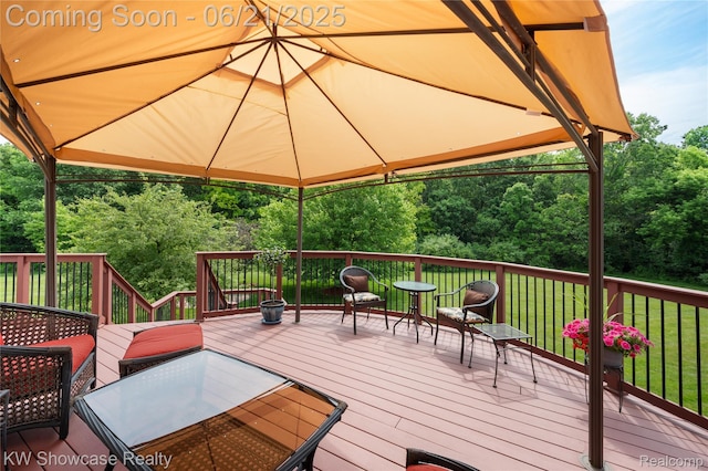 2449 Woodvale Trl, Brighton, MI 48114 - deck with outdoor dining area, view of wooded area, and a lawn