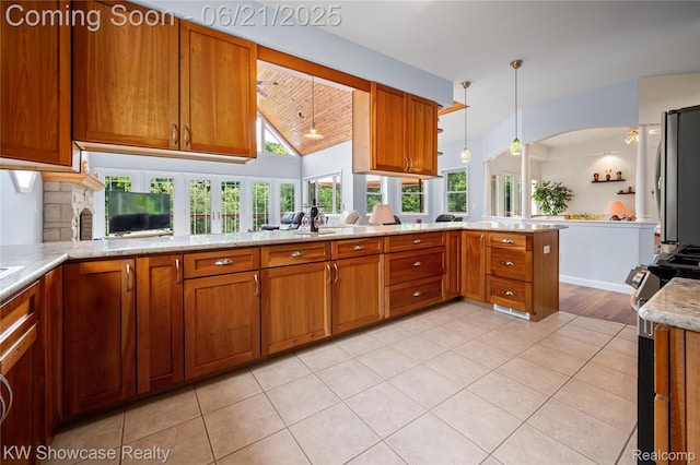 2449 Woodvale Trl, Brighton, MI 48114 - kitchen with stainless steel appliances, brown cabinetry, a peninsula, hanging light fixtures, and vaulted ceiling
