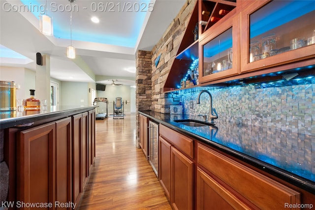 2449 Woodvale Trl, Brighton, MI 48114 - indoor wet bar featuring light wood-style flooring, hanging light fixtures, beverage cooler, backsplash, and a raised ceiling