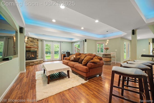 2449 Woodvale Trl, Brighton, MI 48114 - living room with a tray ceiling, wood finished floors, a fireplace, french doors, and recessed lighting