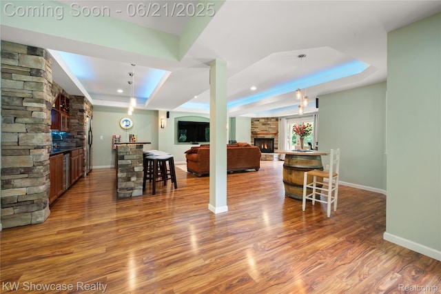2449 Woodvale Trl, Brighton, MI 48114 - kitchen featuring a raised ceiling, a stone fireplace, fridge with ice dispenser, wood finished floors, and hanging light fixtures