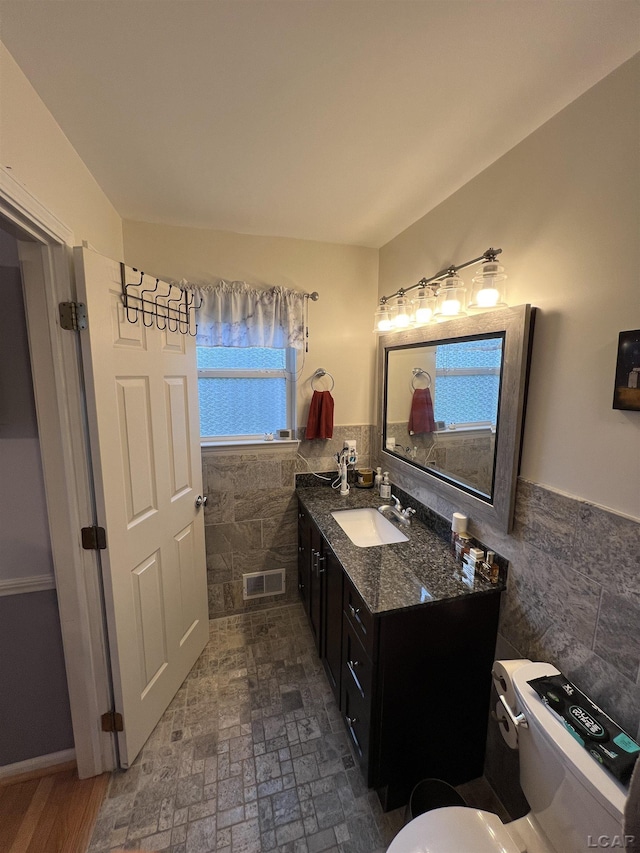 9299 Parkland Dr, Ypsilanti, MI 48197 - bathroom with tile walls, toilet, vanity, and wainscoting