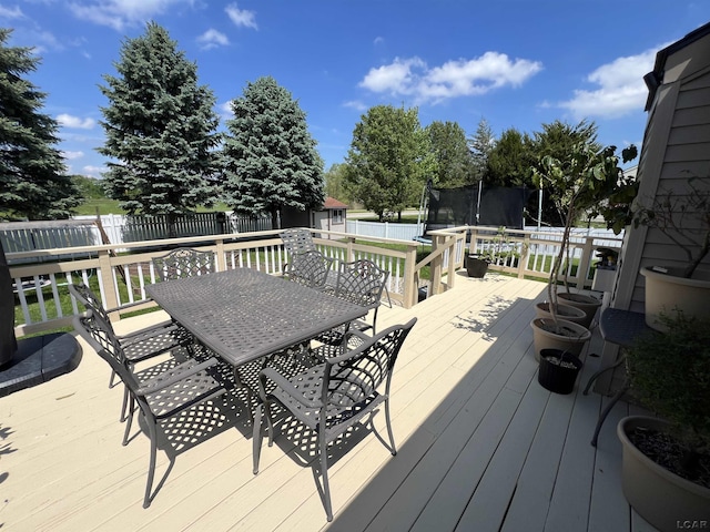 9299 Parkland Dr, Ypsilanti, MI 48197 - wooden terrace with a trampoline, outdoor dining space, a shed, and an outbuilding
