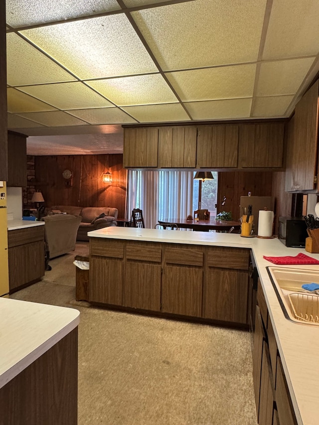 8610 N Waumegah Rd, Clarkston, MI 48348 - kitchen featuring wooden walls, light countertops, a drop ceiling, open floor plan, and a sink