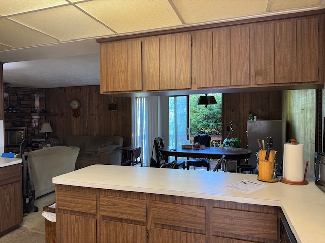 8610 N Waumegah Rd, Clarkston, MI 48348 - kitchen with light countertops, open floor plan, brown cabinetry, and wooden walls