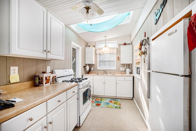 3309 Dumont Lake Dr, Allegan, MI 49010 - kitchen with white appliances, a sink, a skylight, white cabinetry, and wooden walls