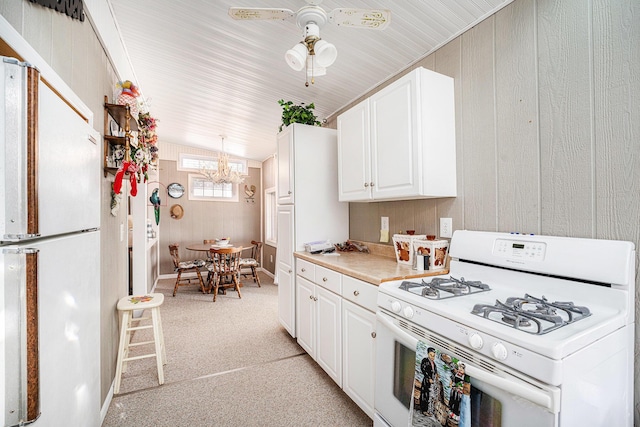 3309 Dumont Lake Dr, Allegan, MI 49010 - kitchen with white appliances, light countertops, white cabinetry, a chandelier, and wood walls