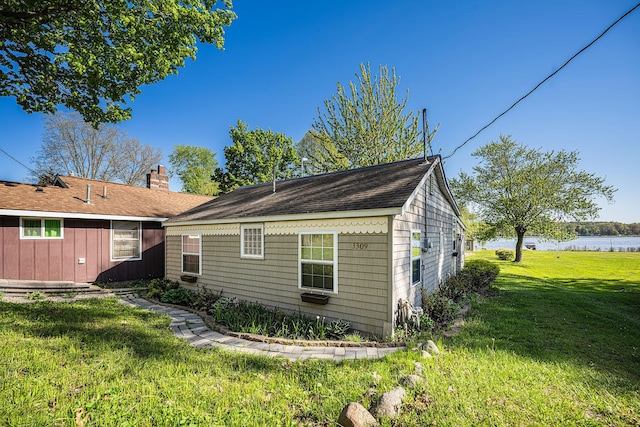 3309 Dumont Lake Dr, Allegan, MI 49010 - view of property exterior featuring a yard, a water view, a chimney, and roof with shingles