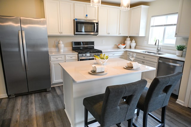 kitchen featuring appliances with stainless steel finishes, a sink, dark wood-style flooring, light countertops, and white cabinetry