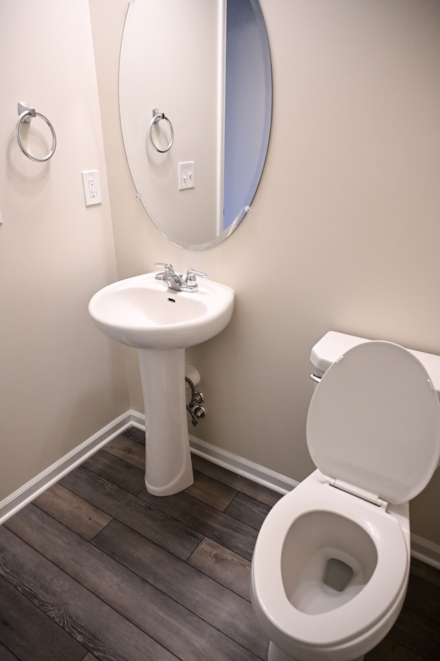 bathroom with wood finished floors, baseboards, and toilet