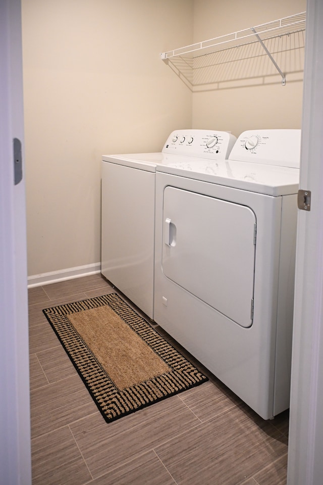 laundry area featuring separate washer and dryer, baseboards, and wood finish floors