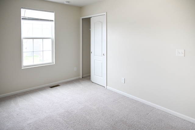 carpeted spare room featuring plenty of natural light and baseboards