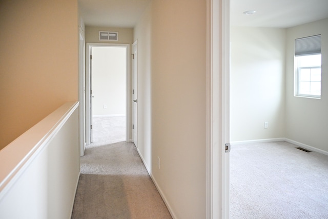 hall featuring light colored carpet and baseboards