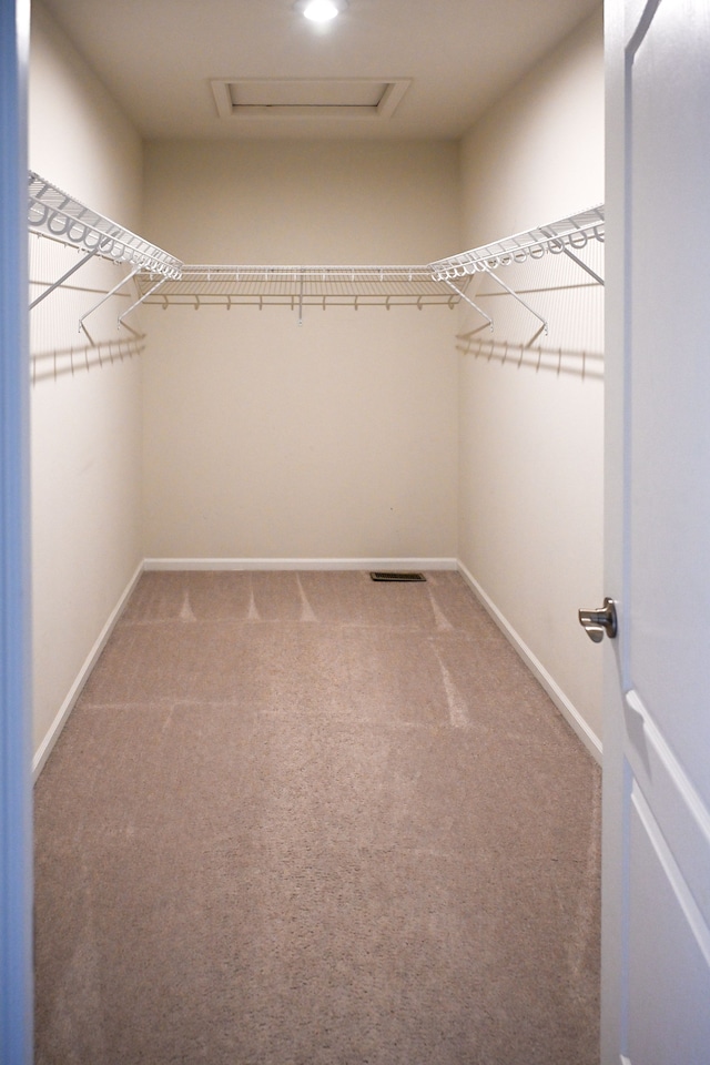 spacious closet with attic access and light colored carpet
