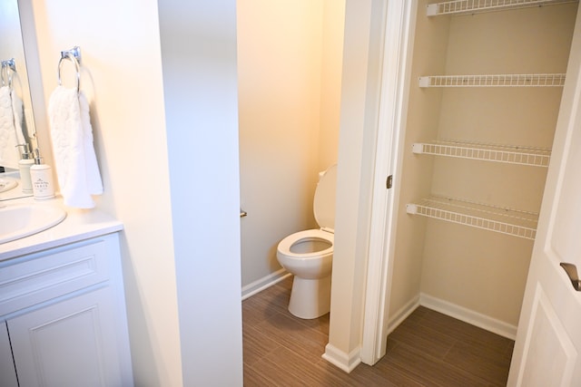 bathroom featuring vanity, toilet, baseboards, and wood finished floors