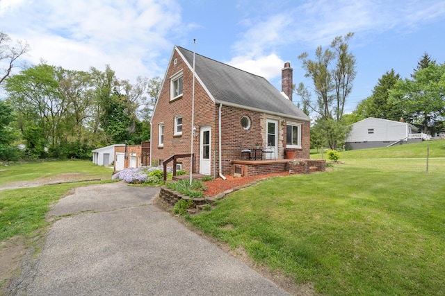 view of property exterior featuring a chimney, an outbuilding, a yard, and brick siding