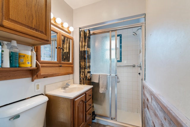 full bathroom featuring a stall shower, vanity, and toilet