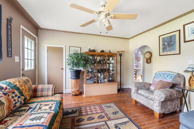 living room featuring arched walkways, wood finished floors, ceiling fan, and baseboards
