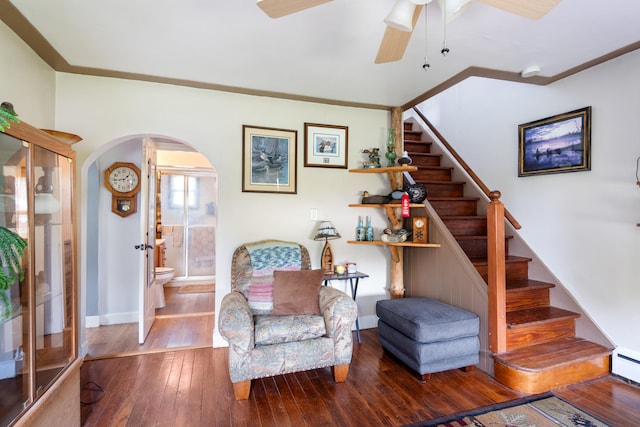 living area with arched walkways, hardwood / wood-style floors, stairway, a ceiling fan, and baseboards