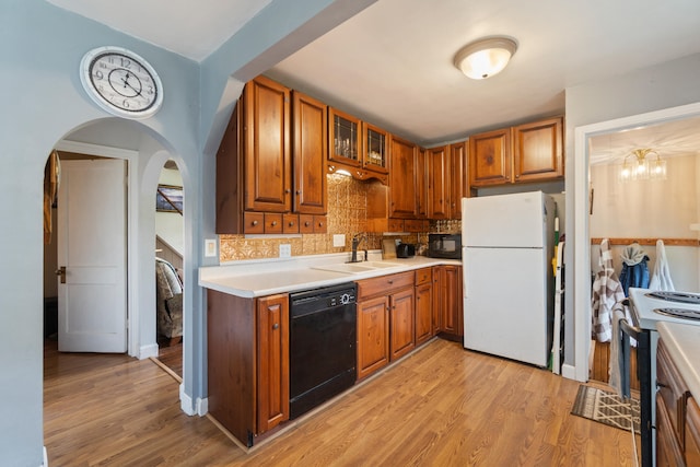 kitchen with black appliances, a sink, light countertops, and brown cabinetry