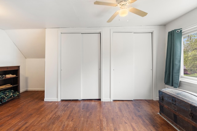 unfurnished bedroom with two closets, wood finished floors, a ceiling fan, and baseboards