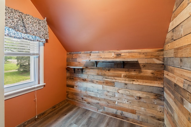 additional living space featuring wood walls, lofted ceiling, plenty of natural light, and wood finished floors