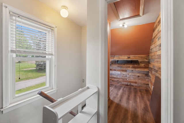 hallway featuring attic access, wood finished floors, and wooden walls