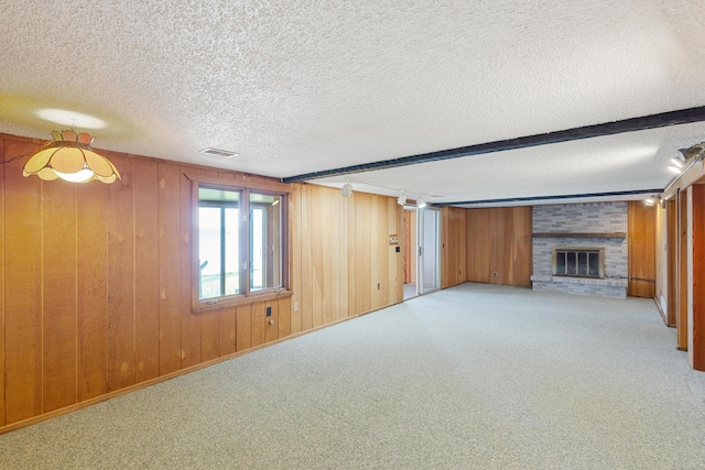 14427 Acorn Cove Trl, Battle Creek, MI 49017 - unfurnished living room featuring wooden walls, a textured ceiling, a fireplace, carpet flooring, and beamed ceiling