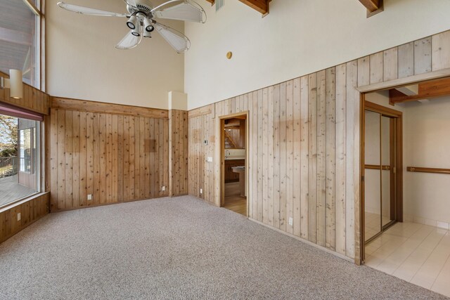 14427 Acorn Cove Trl, Battle Creek, MI 49017 - spare room featuring a high ceiling, a ceiling fan, wood walls, and carpet flooring