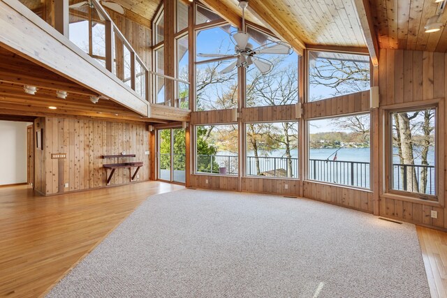14427 Acorn Cove Trl, Battle Creek, MI 49017 - unfurnished living room with ceiling fan, wooden walls, high vaulted ceiling, a water view, and wood finished floors