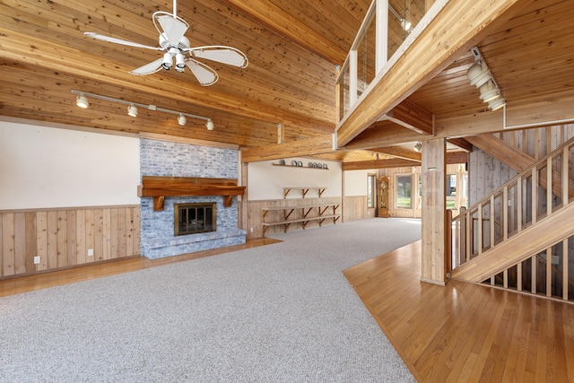 14427 Acorn Cove Trl, Battle Creek, MI 49017 - unfurnished living room with rail lighting, wooden walls, hardwood / wood-style floors, a ceiling fan, and stairs