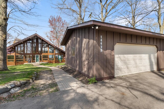 14427 Acorn Cove Trl, Battle Creek, MI 49017 - view of side of property with board and batten siding, asphalt driveway, and a detached garage