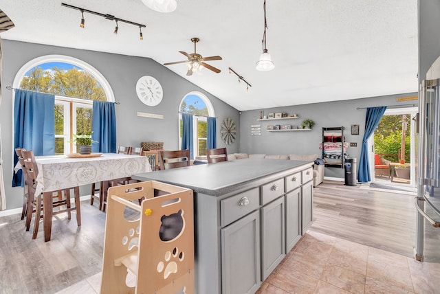 144 Westshore Dr, Jerome, MI 49249 - kitchen with rail lighting, vaulted ceiling, ceiling fan, gray cabinetry, and a center island