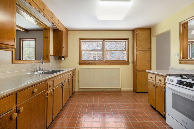 805 E Filer St, Ludington, MI 49431 - kitchen with a sink, white range with gas stovetop, light countertops, baseboards, and brown cabinets